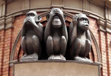 Three wise monkeys statue on a brick building.