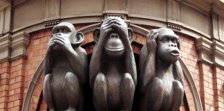 Three wise monkeys statue on a brick building.