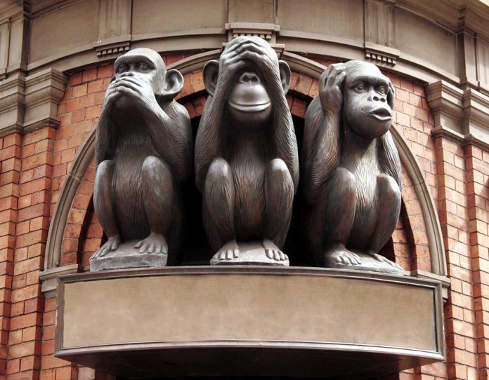 Three wise monkeys statue on a brick building.