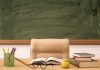 Classroom desk with books, apple, and chalkboard