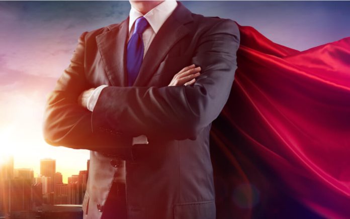 Businessman wearing a cape, standing confidently.