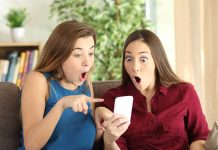 Two women look surprised at a phone.