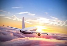 Airplane flying above clouds during sunset sky