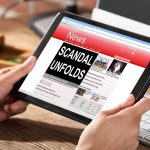 Person holding tablet displaying news headline Scandal unfolds