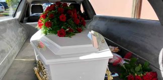 White coffin with red roses inside a hearse