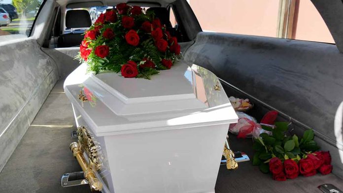 White coffin with red roses inside a hearse