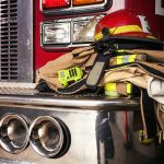 Firefighter gear on a fire truck bumper.