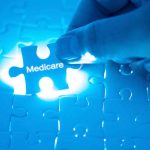 Hand holding Medicare puzzle piece over board