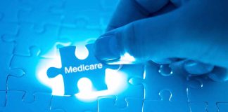 Hand holding Medicare puzzle piece over board