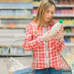 Woman reading label in grocery store aisle