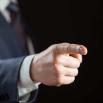 Person pointing with finger, wearing a suit