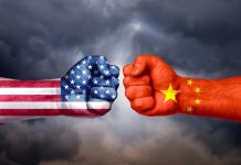 Two fists with US and China flags facing