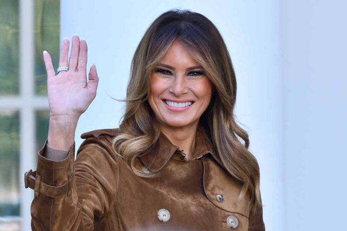 Person smiling and waving wearing a brown coat