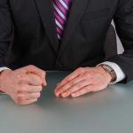 Person in suit with clenched fist on table