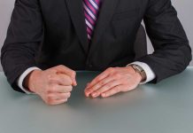 Person in suit with clenched fist on table