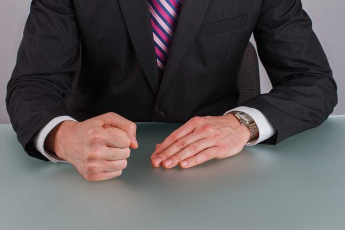 Person in suit with clenched fist on table