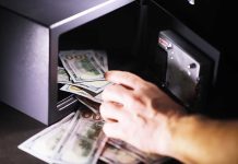 Hand putting cash into a safe