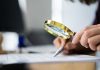 Person examining document with magnifying glass.