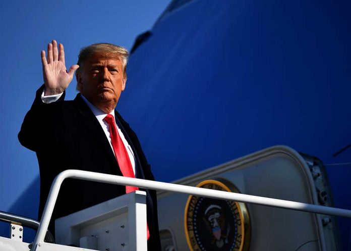 Trump waving from airplane steps.