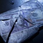 Hundred-dollar bills frozen in cracked ice block