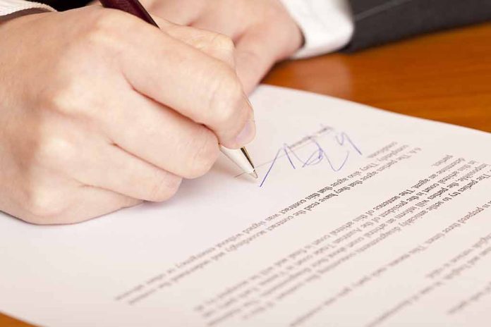 Hand signing a document with a pen.