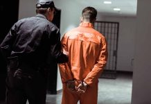 Officer escorting handcuffed prisoner in orange jumpsuit