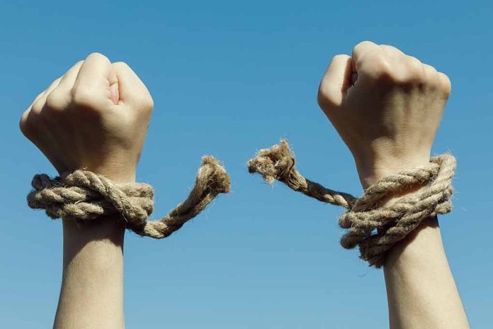 Hands with broken rope against blue sky