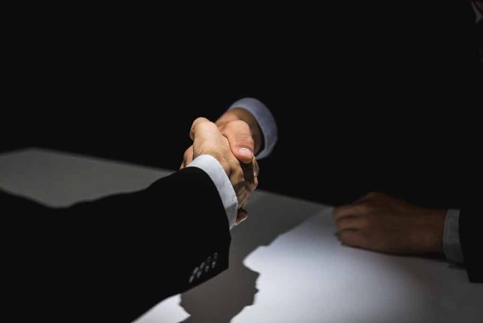 Two people in suits shaking hands.