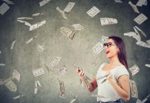 Woman happily holding phone with money flying around