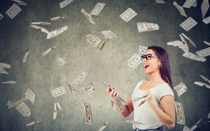 Woman happily holding phone with money flying around