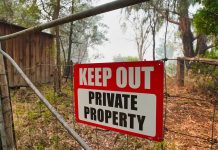 Red Keep Out Private Property sign on gate