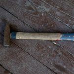 Rusty hammer on a worn wooden floor.