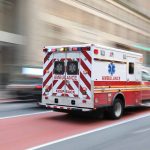 Red and white ambulance driving in the city.