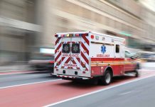 Red and white ambulance driving in the city.