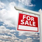 "For sale sign against cloudy sky backdrop."