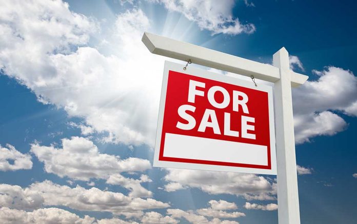 "For sale sign against cloudy sky backdrop."