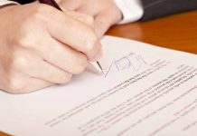 Person signing a document with a pen